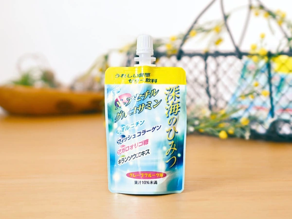 アイスター商事の Ｎ－アセチルグルコサミンを原料に、うれしい食感のゼリー飲料「深海のひみつ」を木製テーブルの上には一、背景にはかごに入った深海のひみつ、エディトリアルな雰囲気。